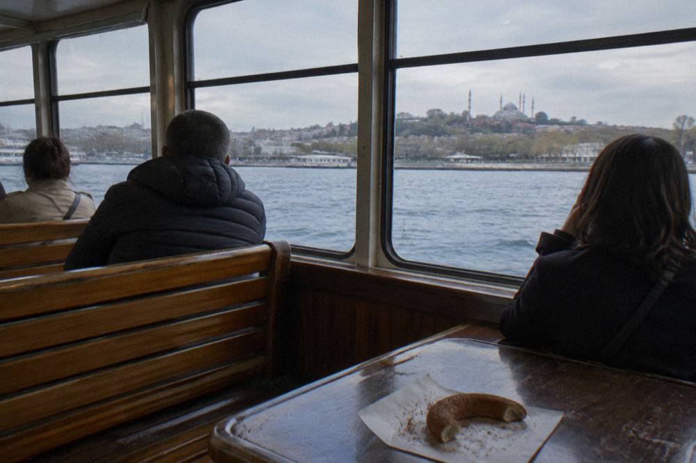 Wooden ferry interior with passengers looking out at the sea on the way to the islands