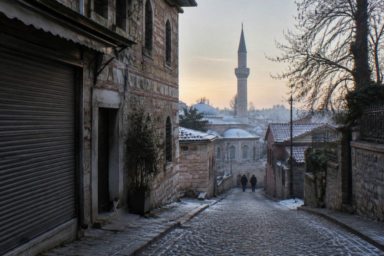 A narrow Istanbul street with historic stone buildings and a mosque minaret rising above the rooftops