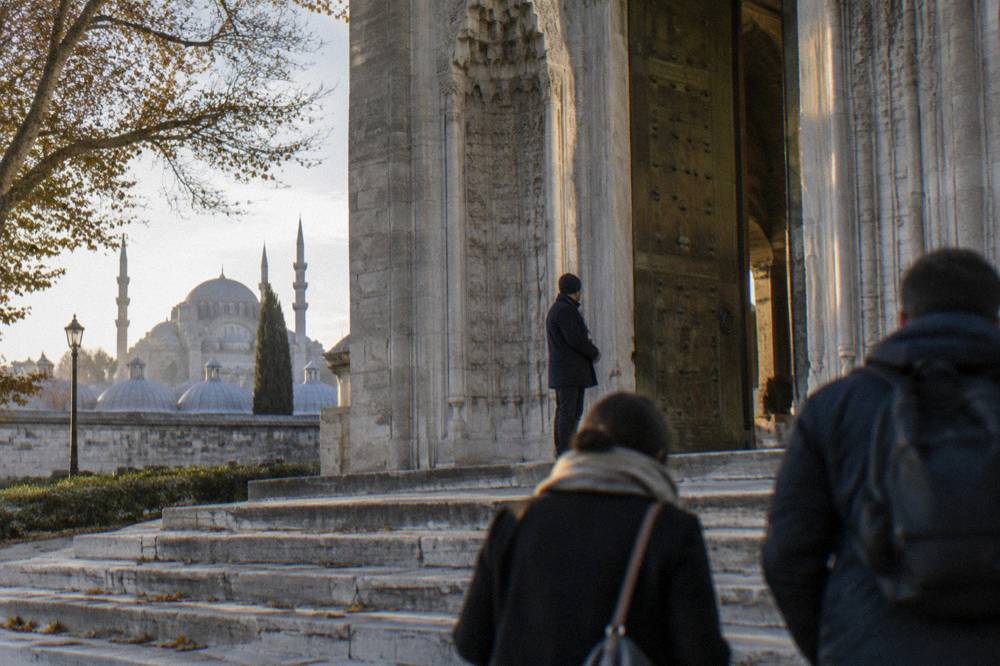 A guide holding up a printed sign beside the gates of Suleymaniye Mosque in Istanbul