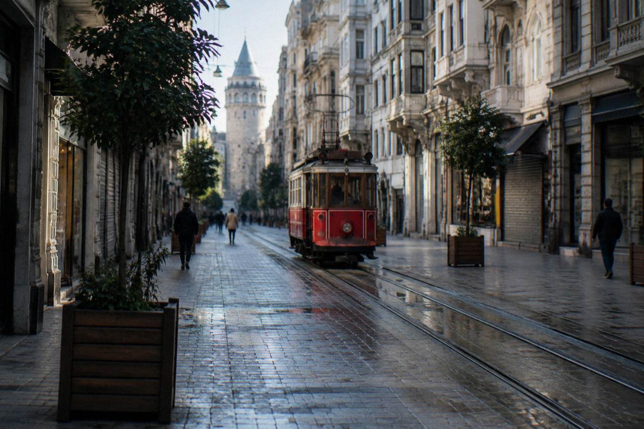 A wide pedestrian avenue lined with historic buildings and a vintage red tram in Istanbul