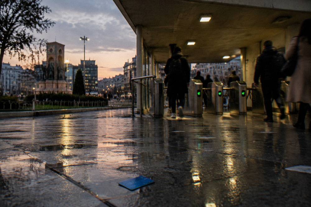 Metro entrance with turnstiles and signage beside a busy city square