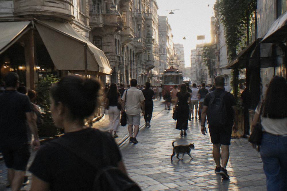 Crowded pedestrian avenue lined with historic buildings and shop awnings in late afternoon light