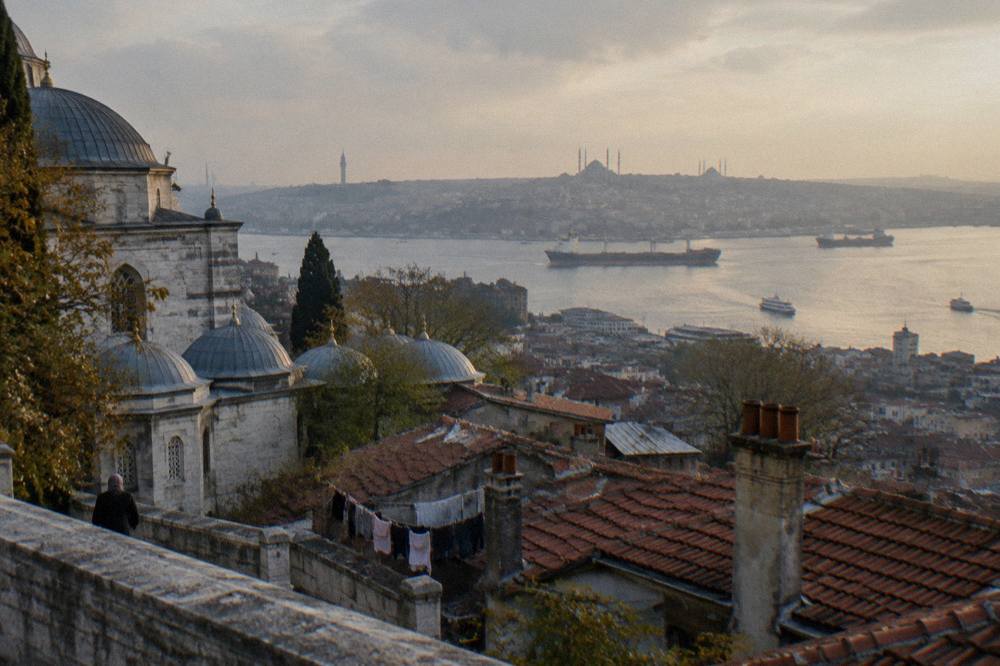 Wide view over Istanbul rooftops toward the Bosphorus strait with ships on the water