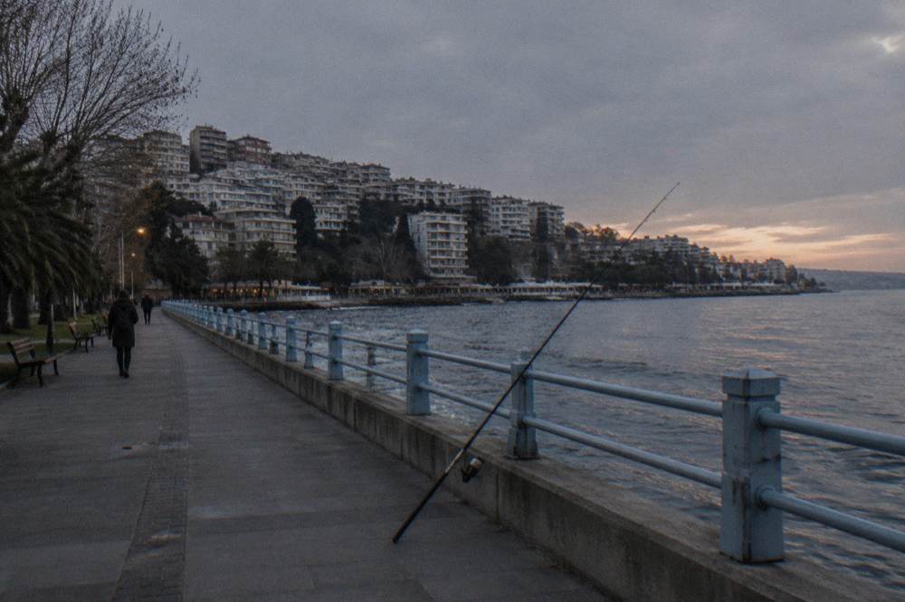 Waterfront promenade in Istanbul with railings along the water and buildings on the hillside