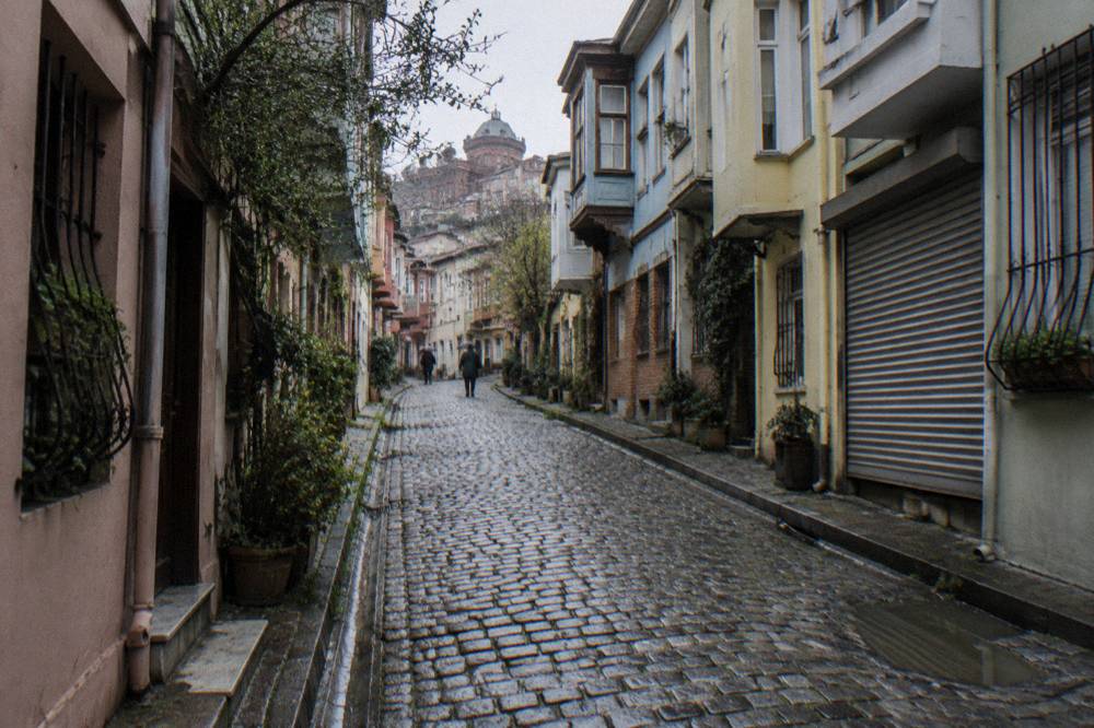 Steep cobbled lane in Fener with pastel apartment buildings on either side