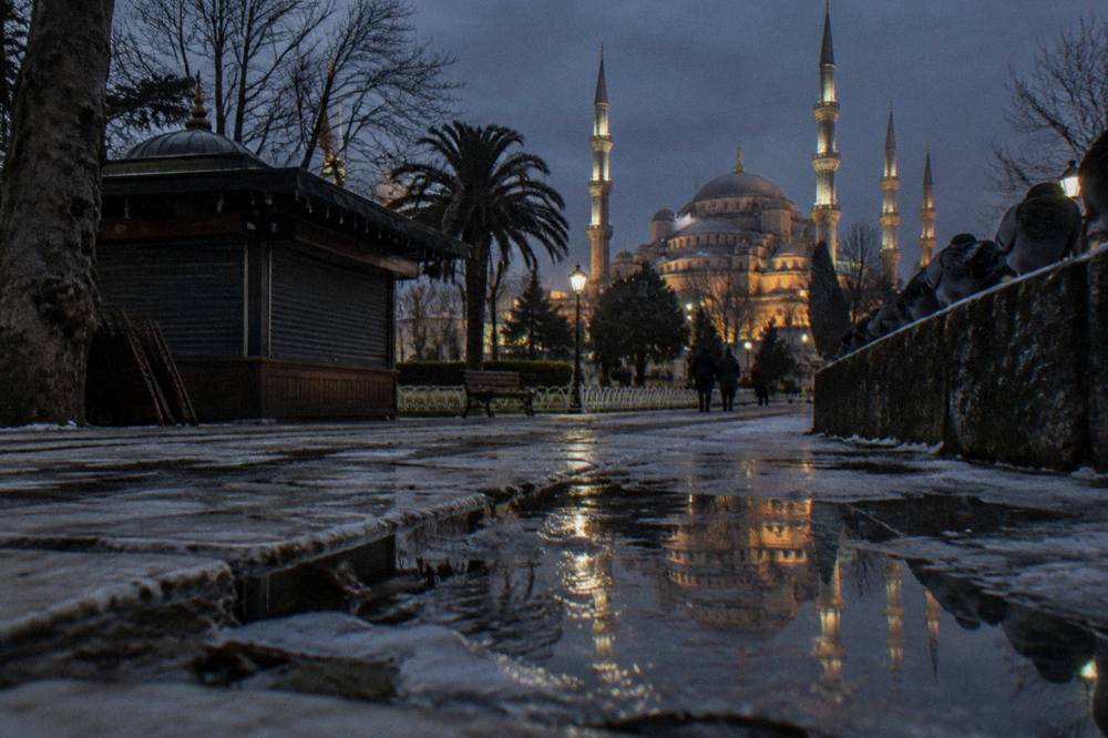 The floodlit domes and minarets of the Blue Mosque seen across Sultanahmet Square at night
