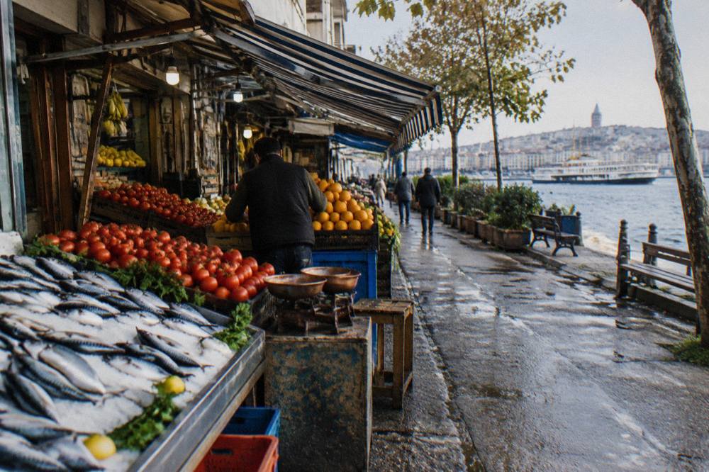 Narrow market street with produce stalls and awnings in a busy Asian side district