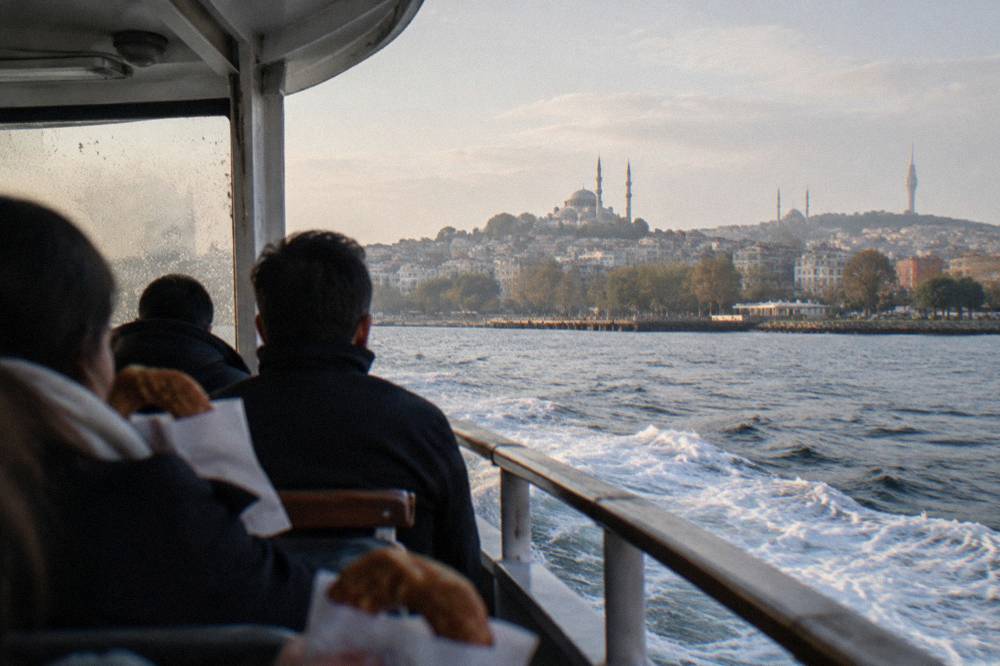 Passenger ferry crossing open water with a city skyline behind it
