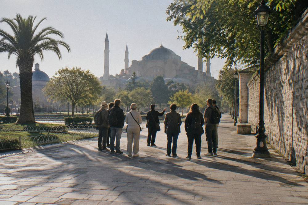 A guide speaking to a small group gathered on a sunny plaza in Istanbul