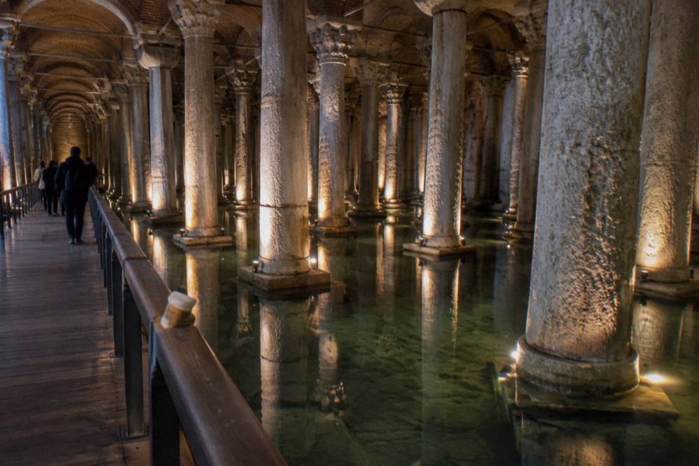 Rows of stone columns reflected in shallow water inside a dim underground cistern