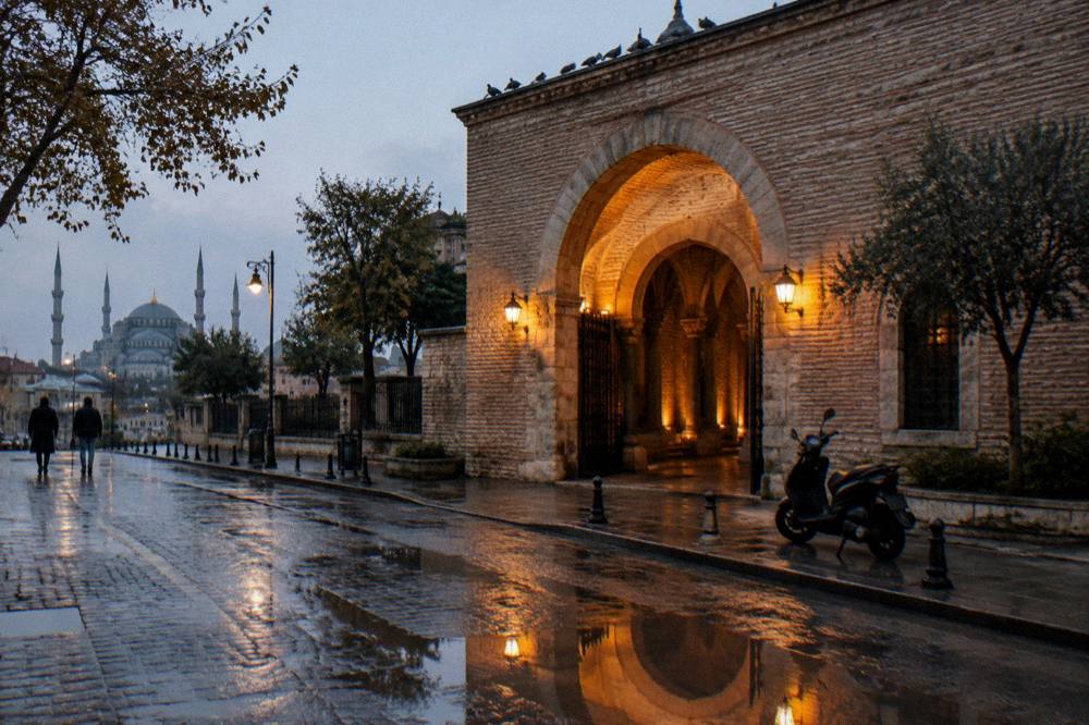The arched stone entrance of an underground cistern set into a city street with warm evening light