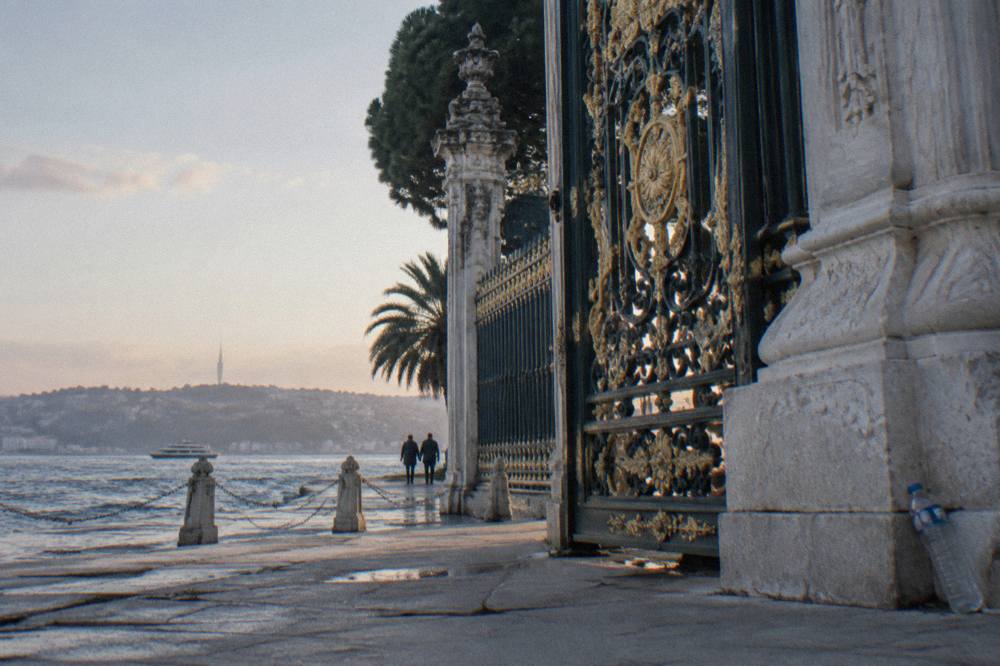 Ornate palace gate with wrought iron details and Bosphorus water behind it