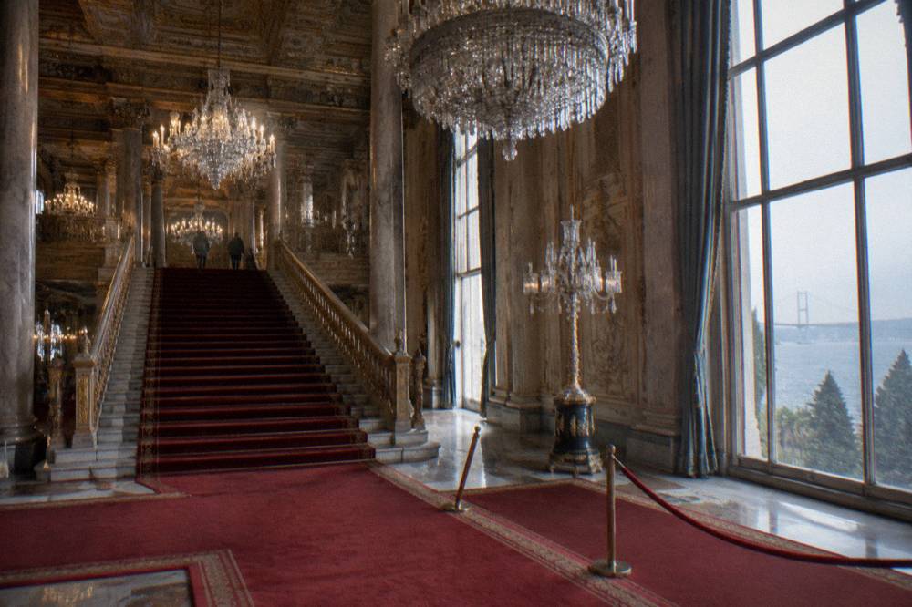 Grand interior hall with crystal chandeliers and a red carpeted staircase