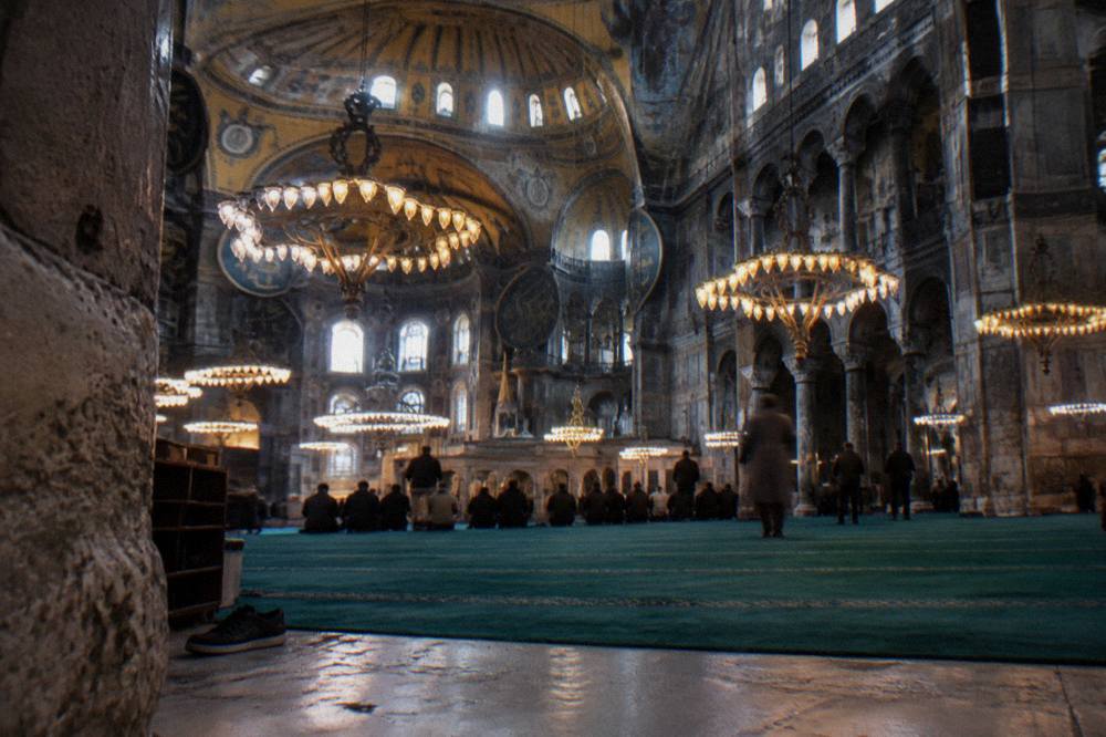 Interior of Hagia Sophia with the vast dome and suspended chandeliers above the ground floor