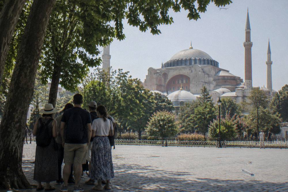 Walking tour group gathered on Sultanahmet Square with Hagia Sophia rising behind the trees