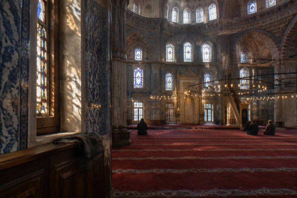 Interior of the Blue Mosque showing blue Iznik tiles, stained glass windows and the carpeted prayer floor