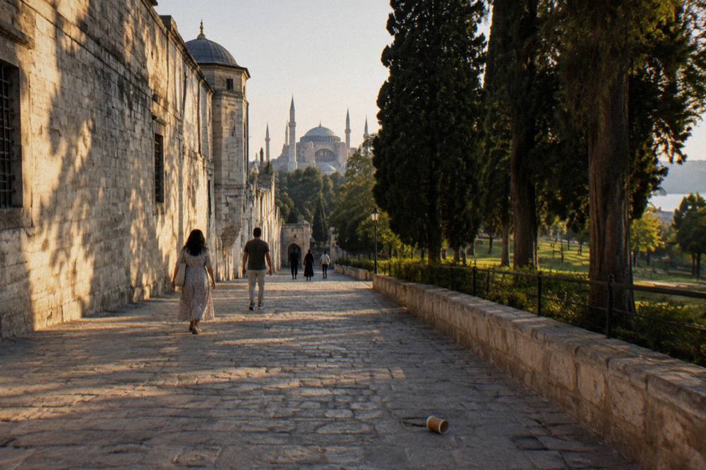 Cobbled outer courtyard of Topkapi Palace with tall stone walls and mature cypress trees